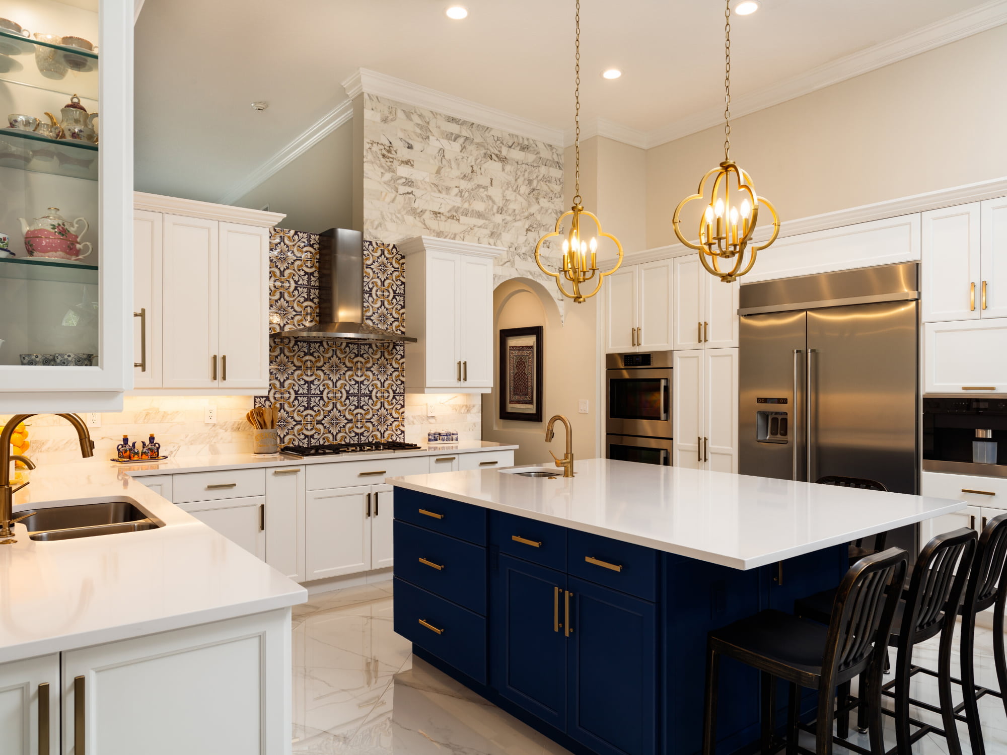 Navy and blue kitchen with brass accents and marble countertops by